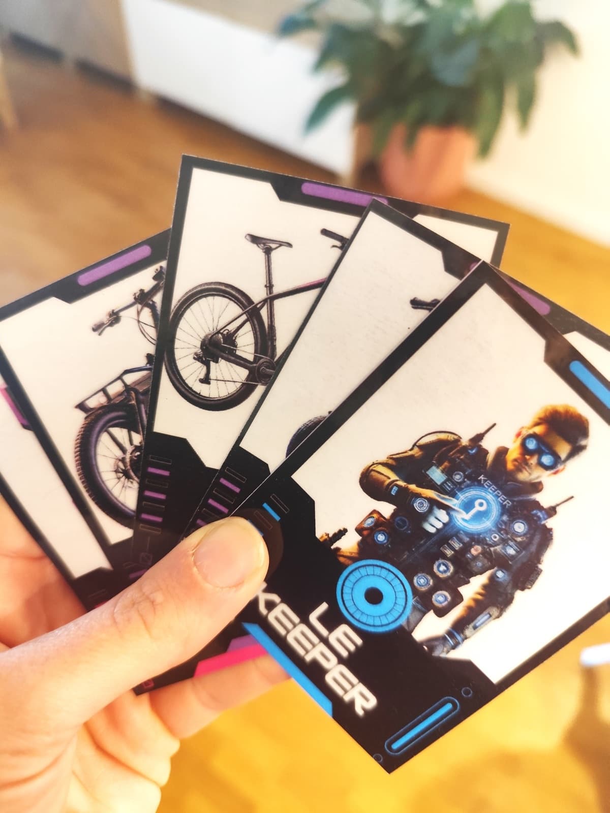 Main tenant en éventail les cartes du jeu « T’es Safe ou tu Keep ? », dont la carte Le Keeper