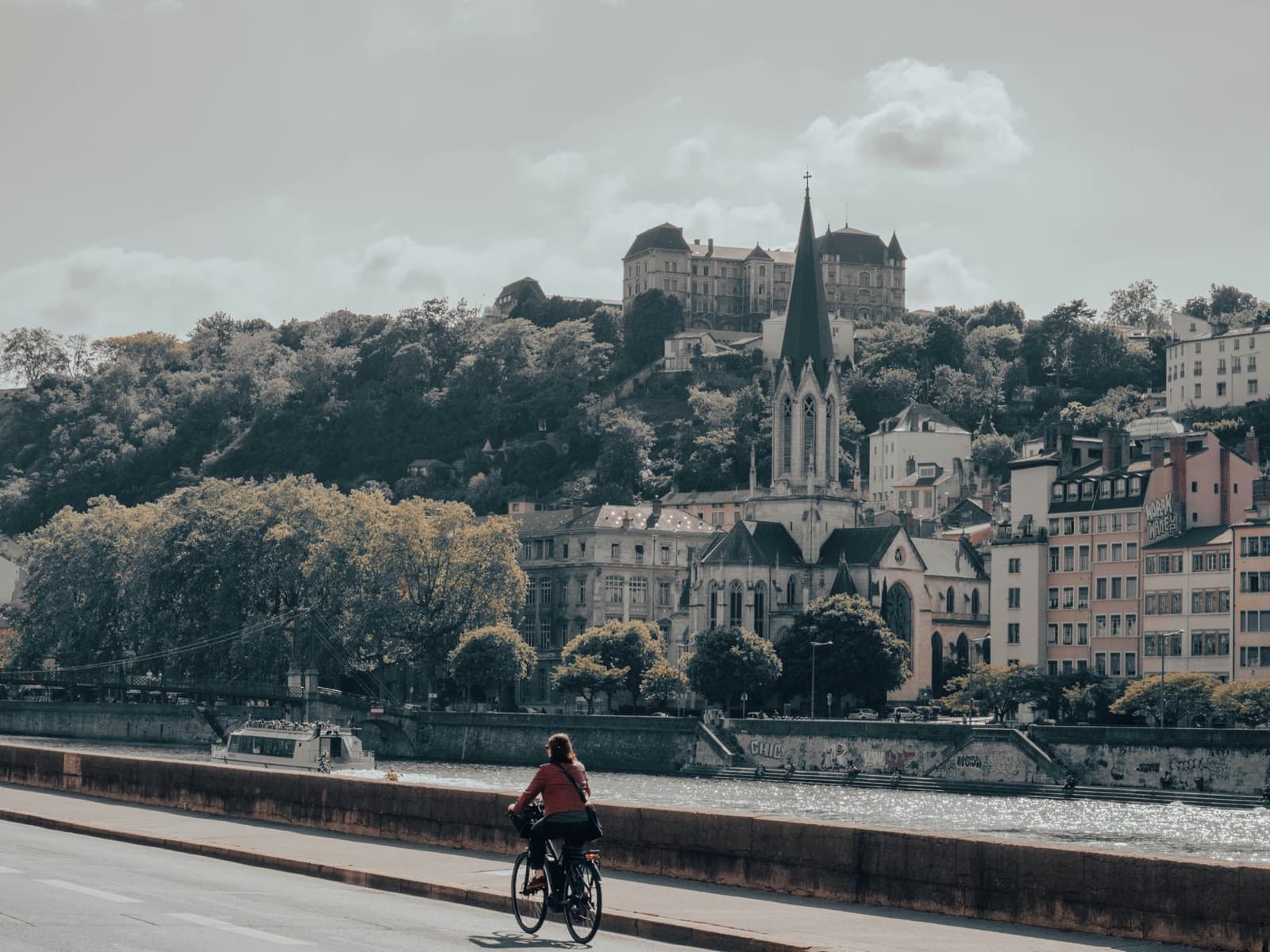 Cycliste sur un quai de Saône à Lyon, avec le Vieux Lyon et la colline de Fourvière en arrière-plan